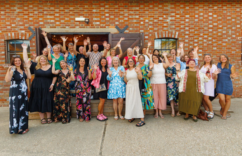 A group photo of the STARS Dorset team of staff, volunteers, trustees, and our patron Jeff Mostyn. They are all smiling and raising their hands in a cheer.